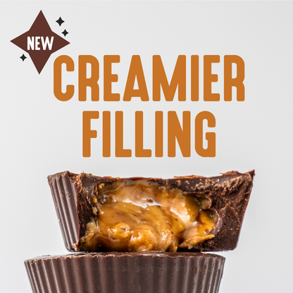 A close-up of Dark Chocolate Peanut Butter Cups reveals creamy filling, stacked on another cup. Text reads New Creamier Filling in bold brown with a decorative starburst next to New on a plain white background, highlighting its keto-friendly nature.